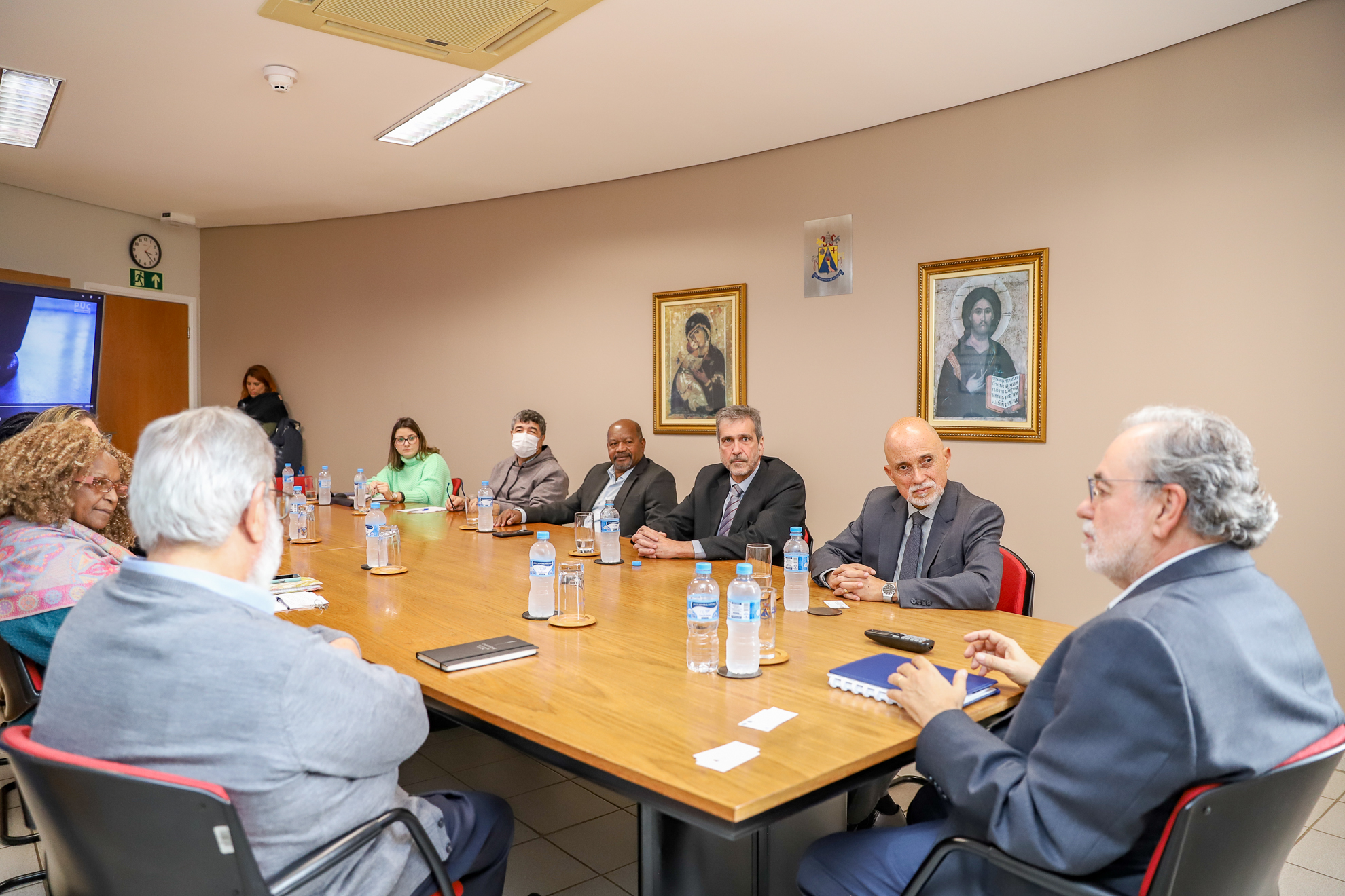 Participantes da reunião estão sentados à mesa, com Dr. Bosco e Dr. Samuel em primeiro plano.