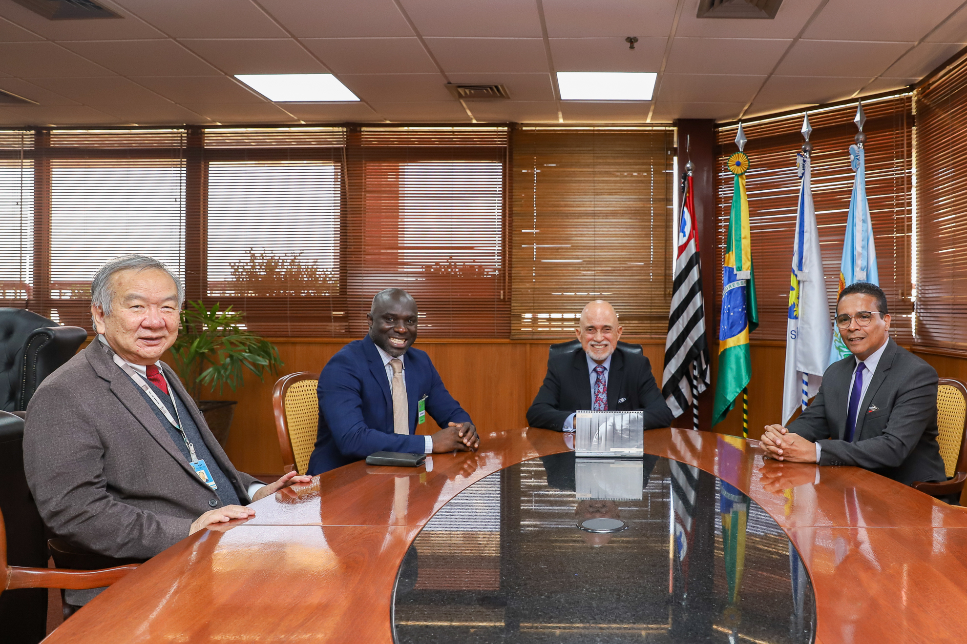 Presidente Samuel está sentado à mesa oval com os representantes da instituição e o assessor Koga