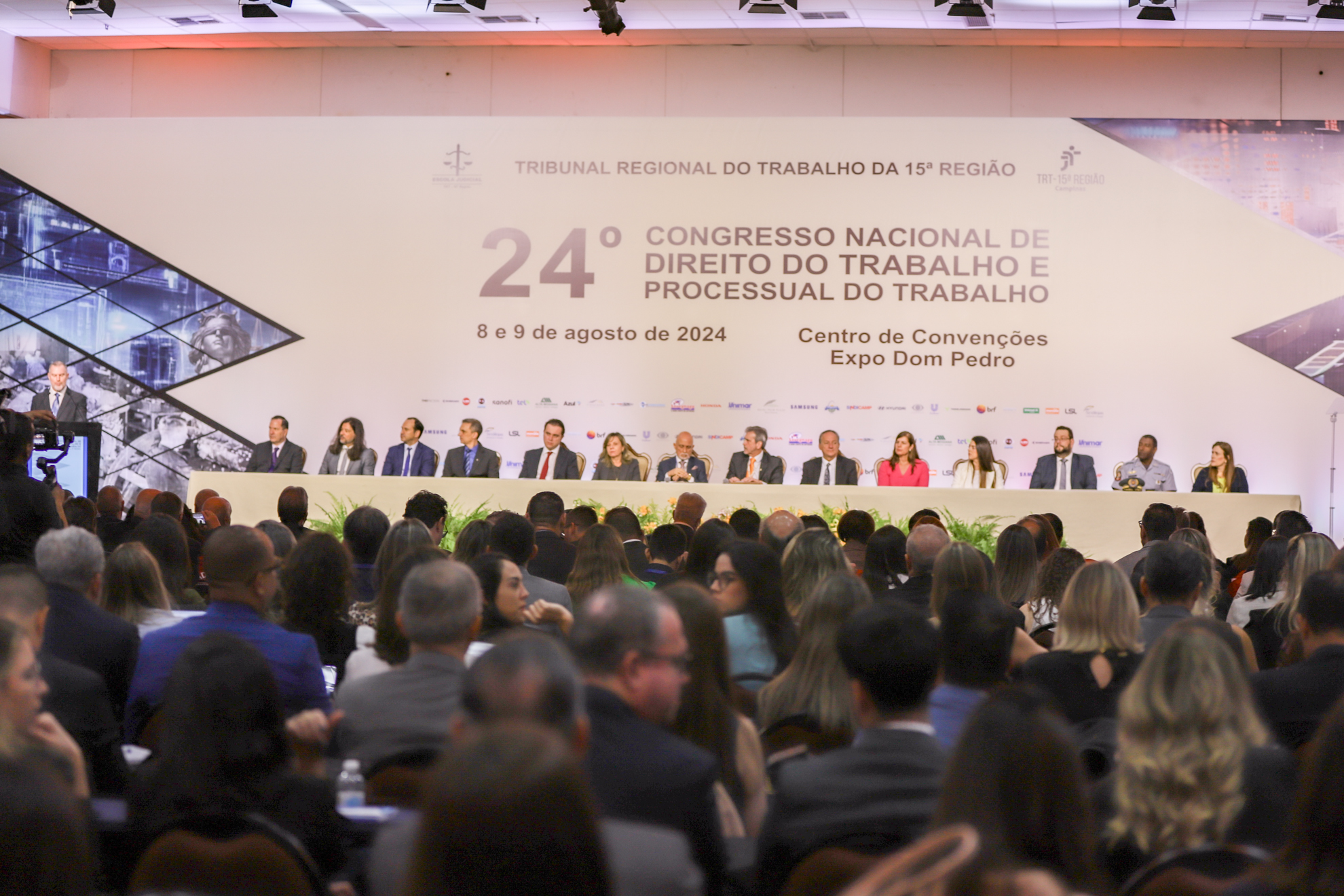 Na Mesa de Honra, integrantes do Congresso Nacional de Direito do Trabalho. Em primeiro plano, sentado, o público do evento.