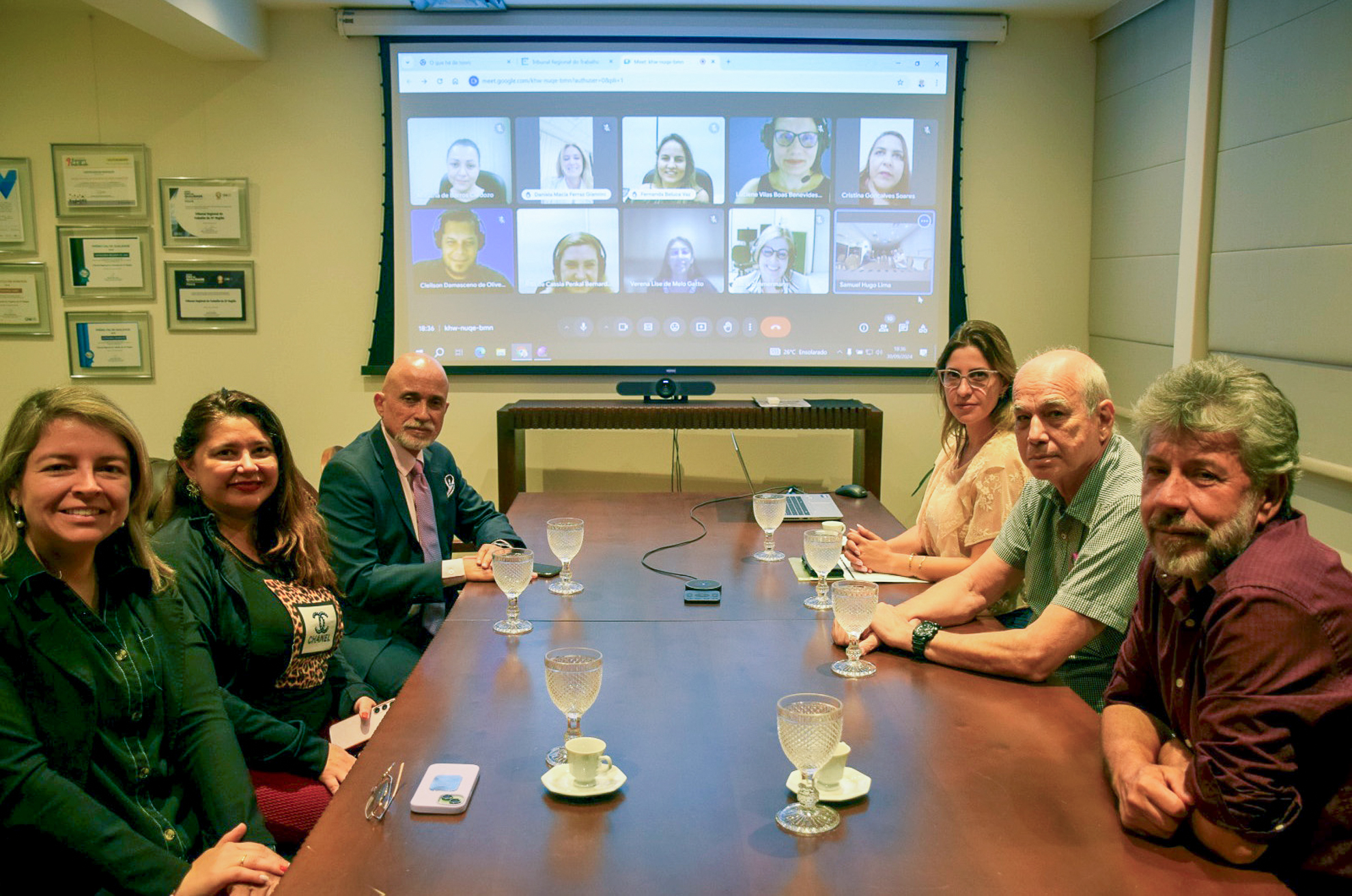 Presidente Samuel em mesa de reunião com servidores. Ao fundo demais participantes em telão.