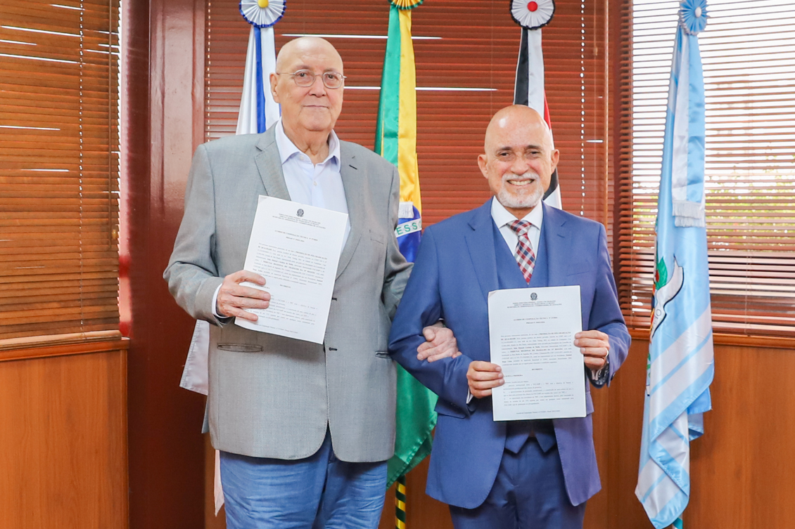 João Manuel e o desembargador Samuel Lima posam para a foto, em pé, segurando o Termo assinado. Eles  