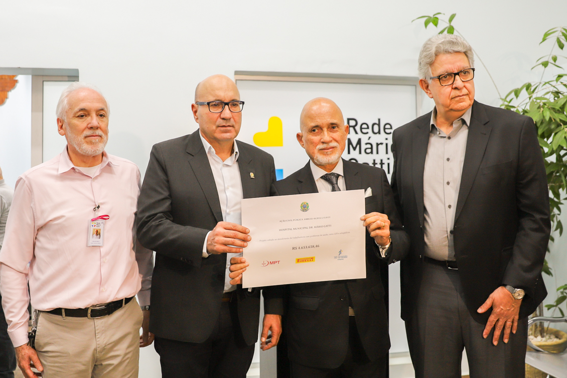 O desembargador Samuel e o prefeito Dário posam para a foto segurando o cheque simbólico. Posam para a foto também os dois representantes do hospital.