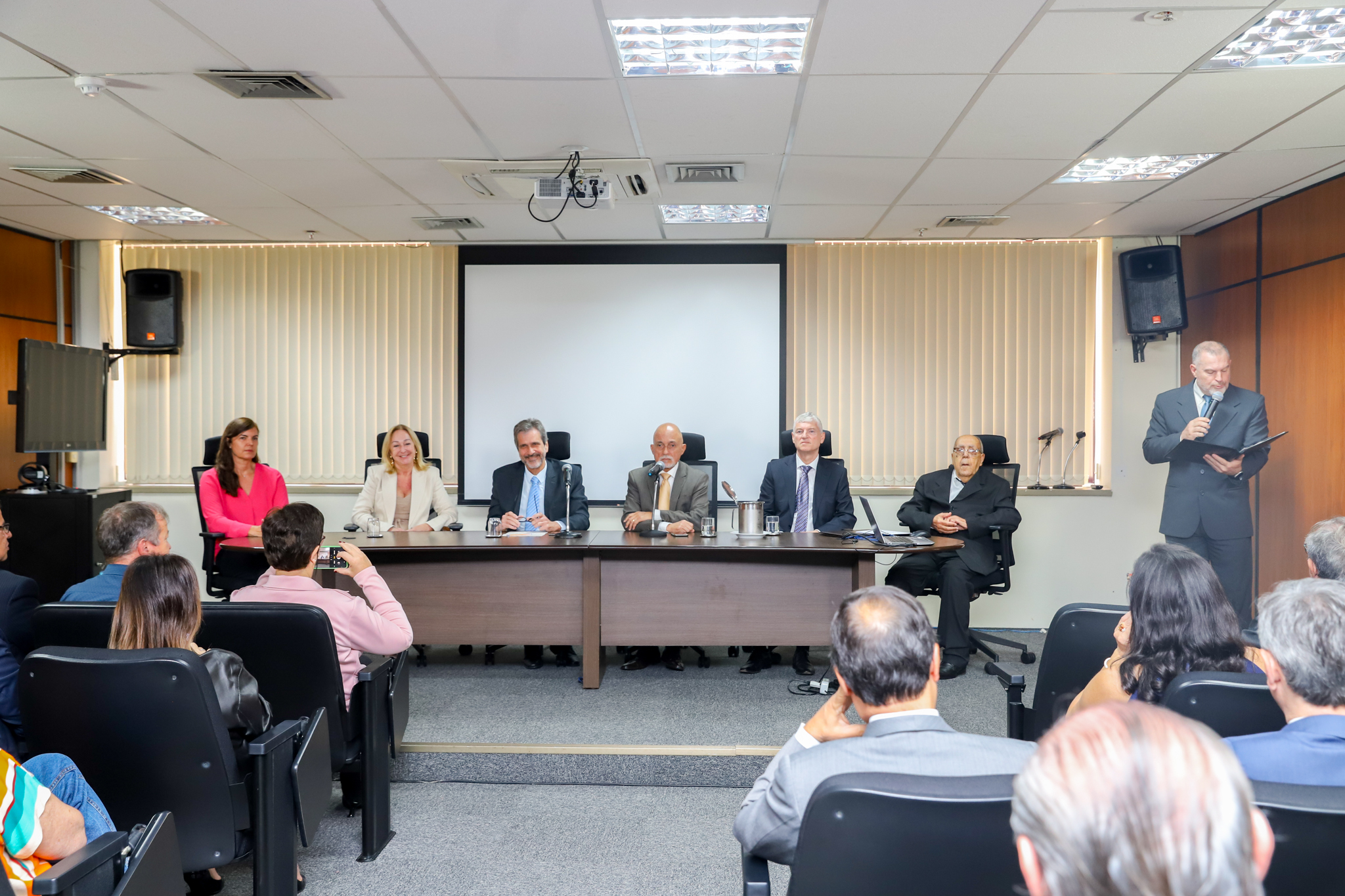 imagem dos componentes da mesa, com o cerimonialista à direita da tela, abrindo os trabalhos