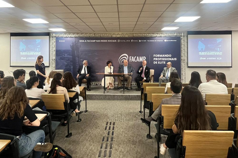 foto geral do auditório da Facamp com a mesa de abertura ao fundo e alunos na plateia