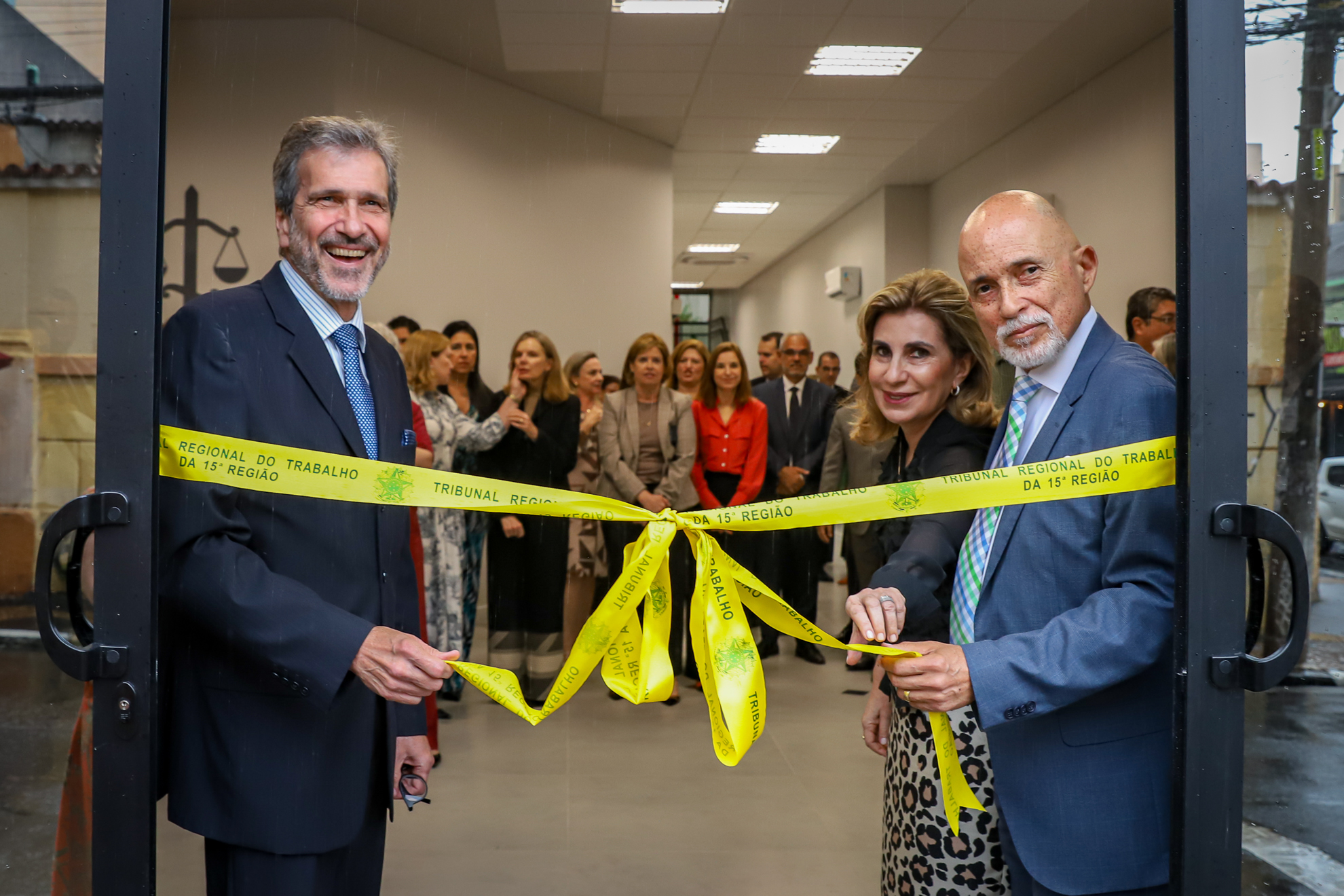 Dr. Carlos Bosco, Dra. Ana Paula Lockmann e Dr. Samuel fazem o desenlace da fita na porta do novo prédio, sendo observados pelo público.