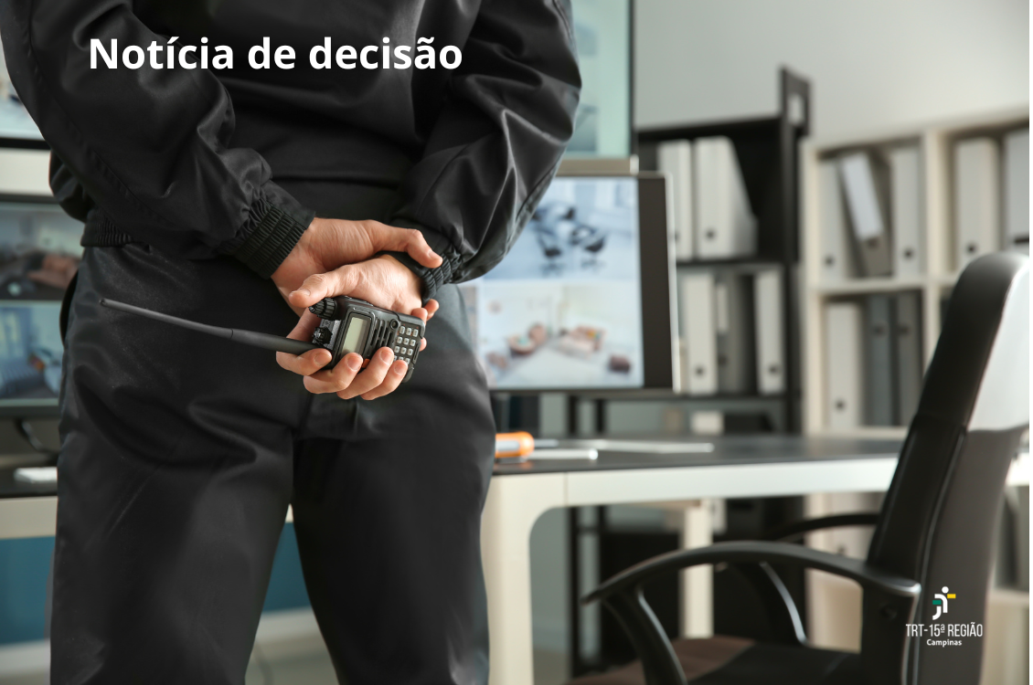 imagem mostra um vigilante de costas, segurando um comunicador, em ambiente de trabalho