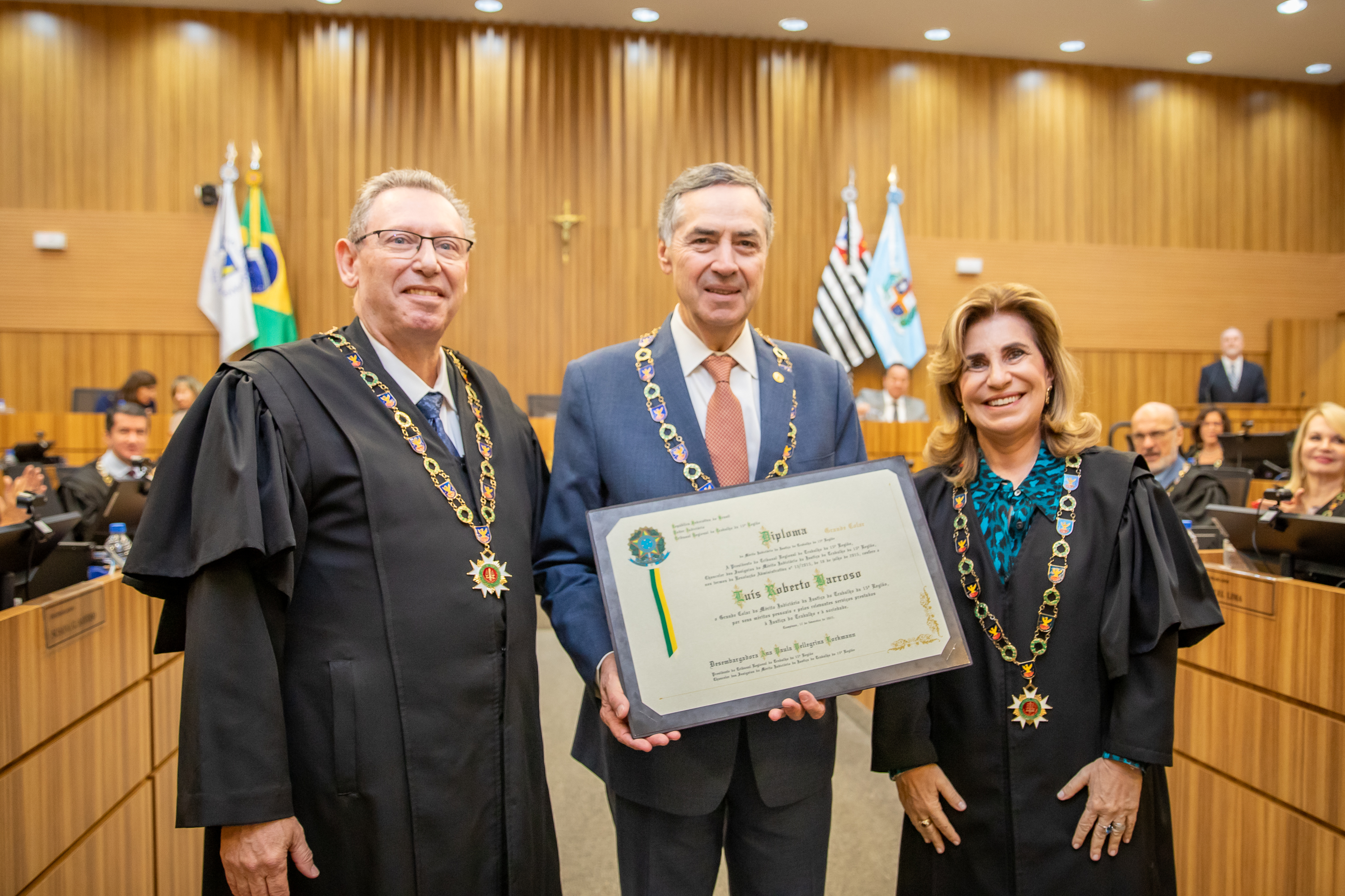 ministro Barroso com o Grande Colar está entre os desembargadores Fabio Cooper e Ana Paula, segurando o diploma no Plenário