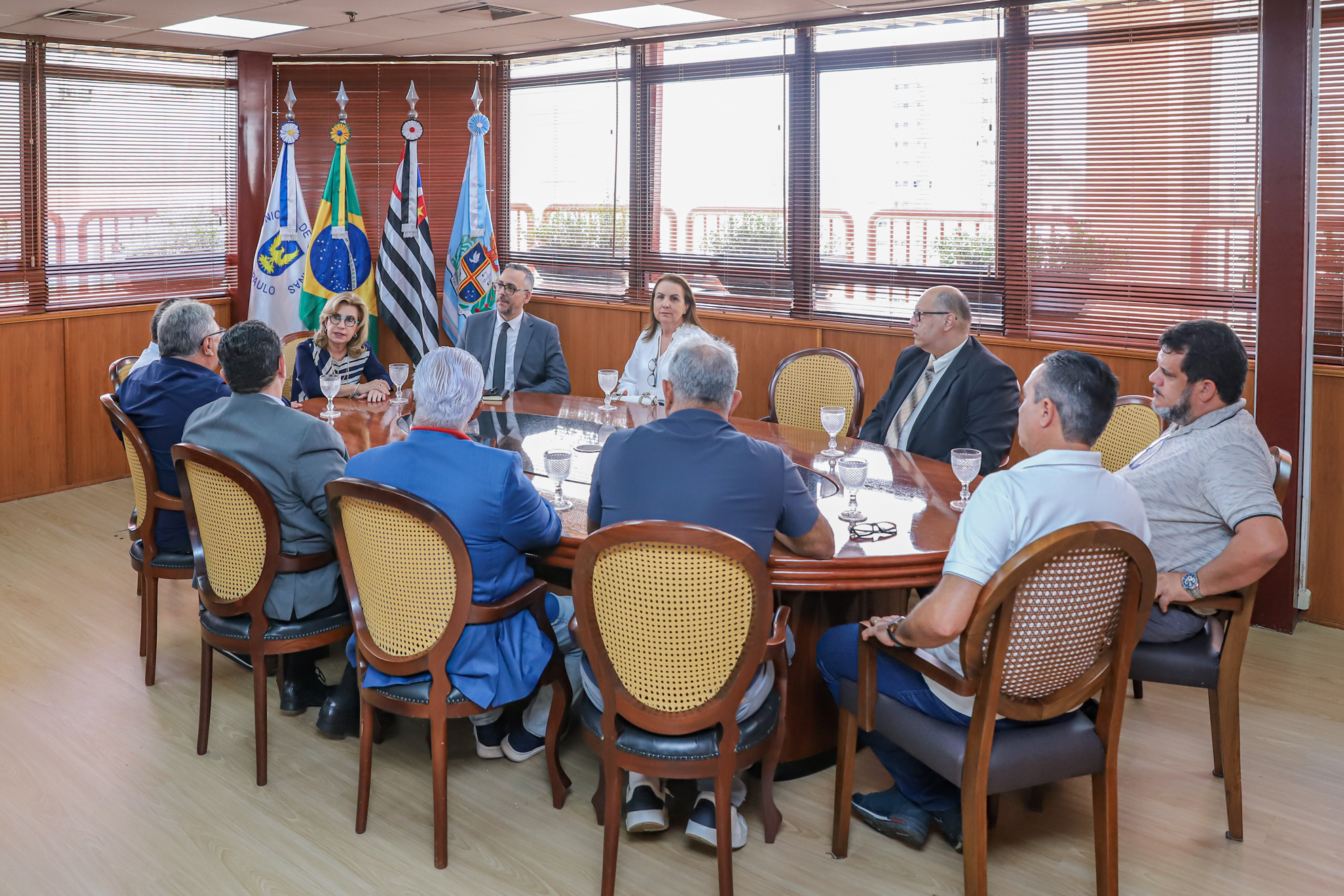 Presidente Ana Paula coordenada reunião em seu gabinete com os participantes sentados à  mesa