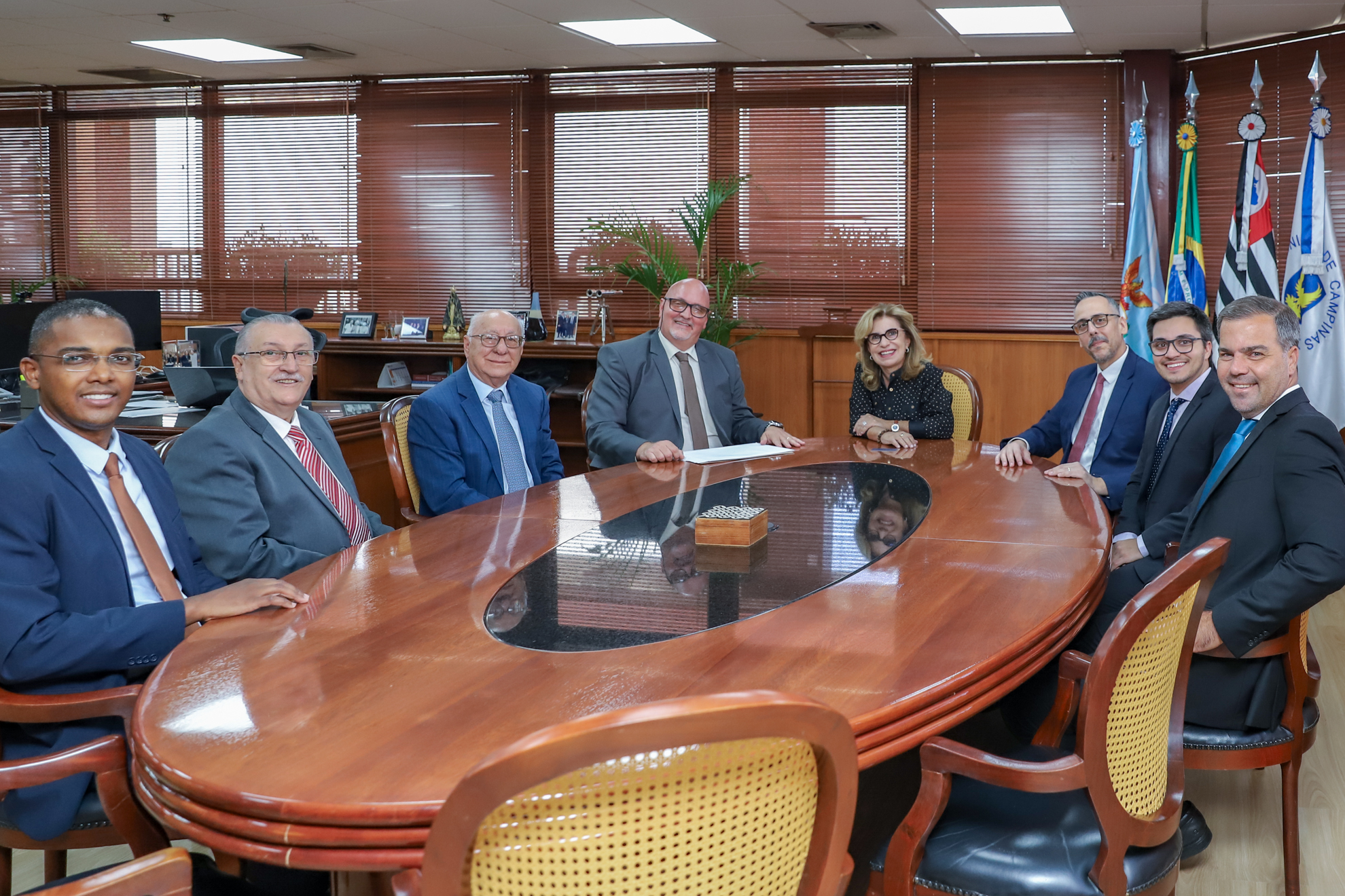 representantes da OAB de Bebedouro em mesa oval de madeira no gabinete da presidência, com a Dra. Ana Paula e Dr. Polastro