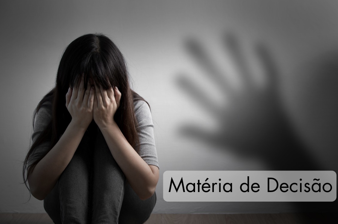 imagem com fundo cinza e uma mulher agachada e olhos tampados pelas mãos. Ao fundo, a sombra de uma mão.