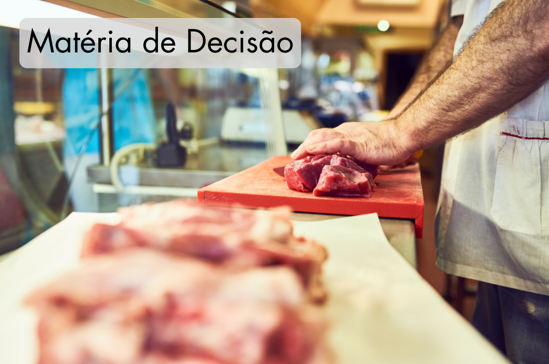 A foto retrata um açougueiro cortando um pedaço de carne.