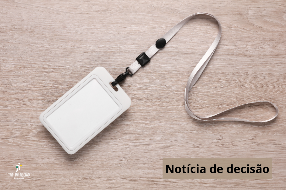 crachá de identificação sobre uma mesa de madeira. À esquerda da tela, a assinatura do TRT-15. À direita, os dizeres: Noticia de decisão, em preto.