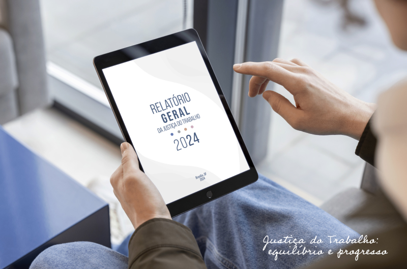 uma pessoa segura um ipad com a capa do relatório estampado na tela. No rodapé direito da imagem, há os dizeres: Justiça e Trabalho, equilíbrio e progresso.