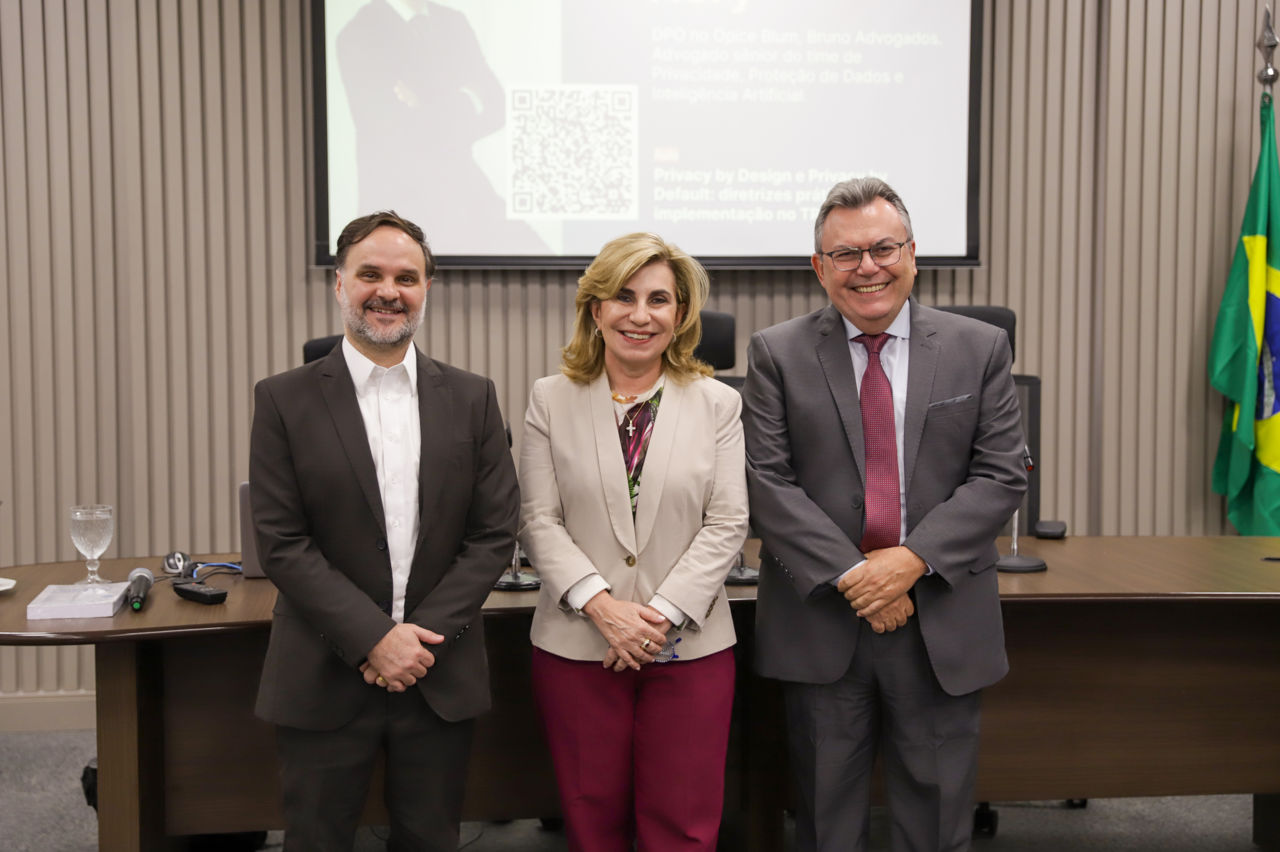 dois homens e uma mulher posam em pé para foto