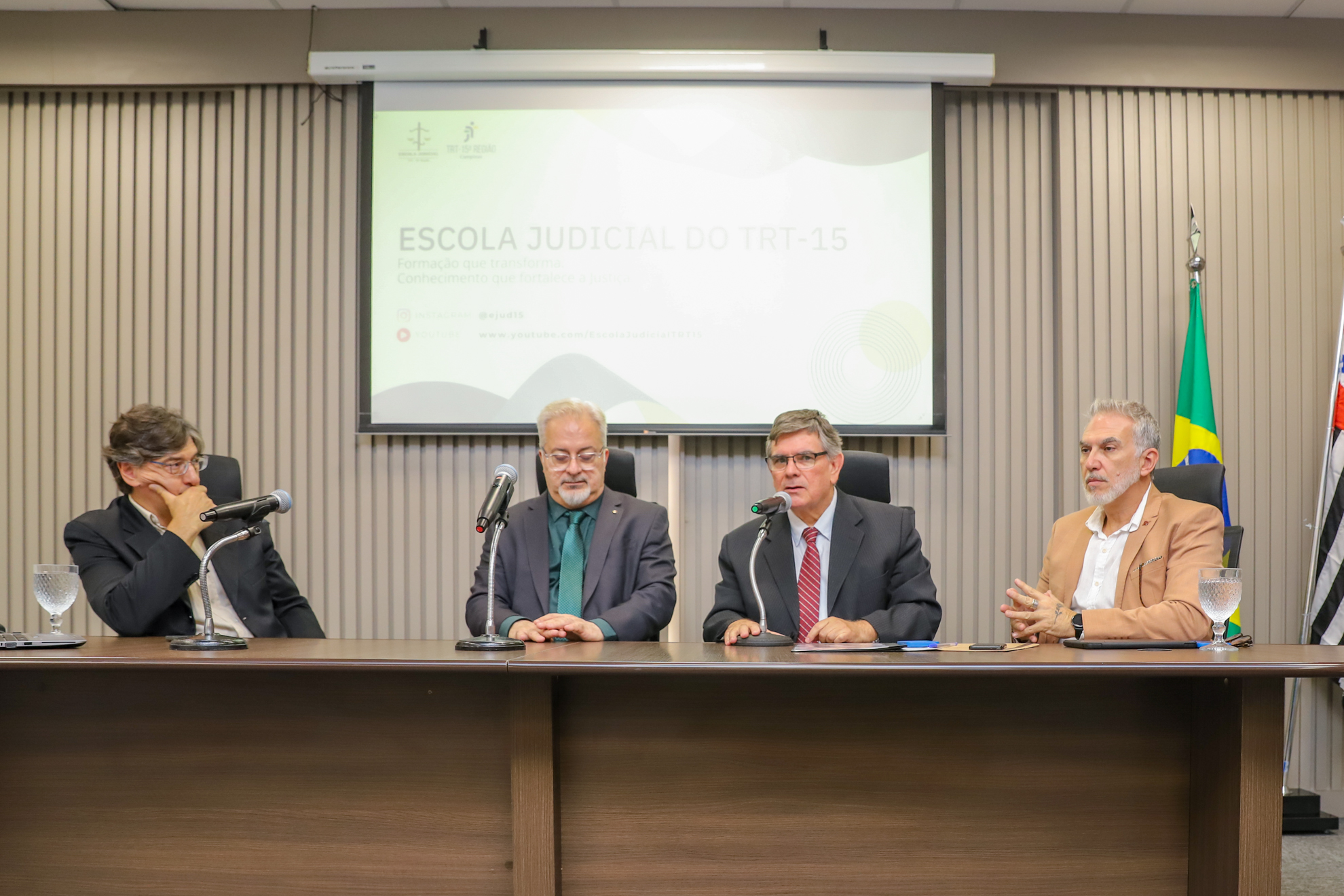 Pochmann, e Drs. Lobo, João Alberto e Carlos Eduardo sentados à mesa alta, com um telão atrás