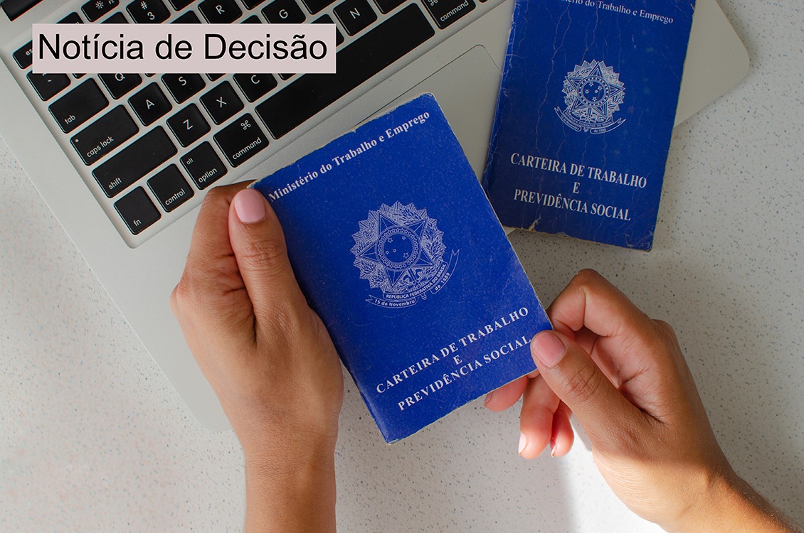 A foto retrata uma mão segurando uma carteira de trabalho.