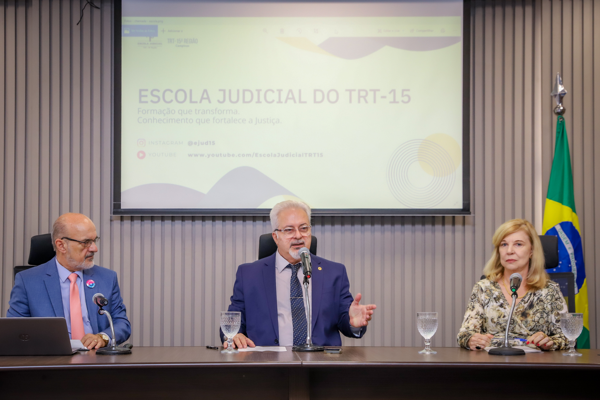Dr. Edmundo, Dr. Lobo e Dra. Antônia estão sentados à mesa de trabalhos no auditório da Ejud-15