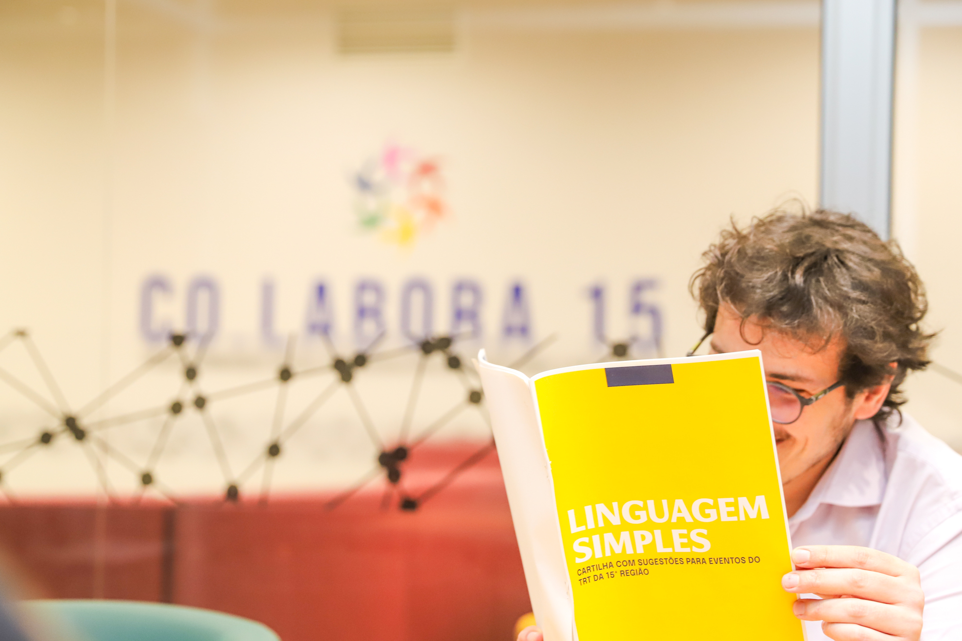 servidor segura cartilha de capa amarela sobre linguagem simples no ambiente do Co.Labora 15