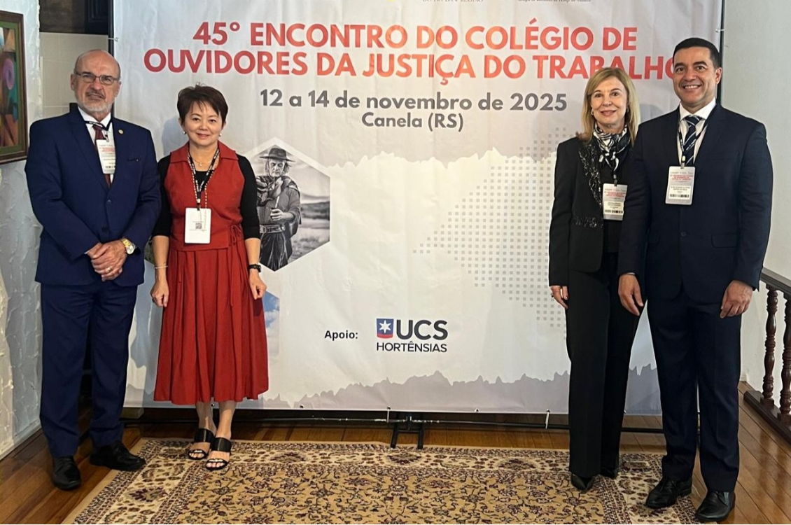 Comitiva do TRT-15 posa para foto em frente ao banner alusivo ao evento