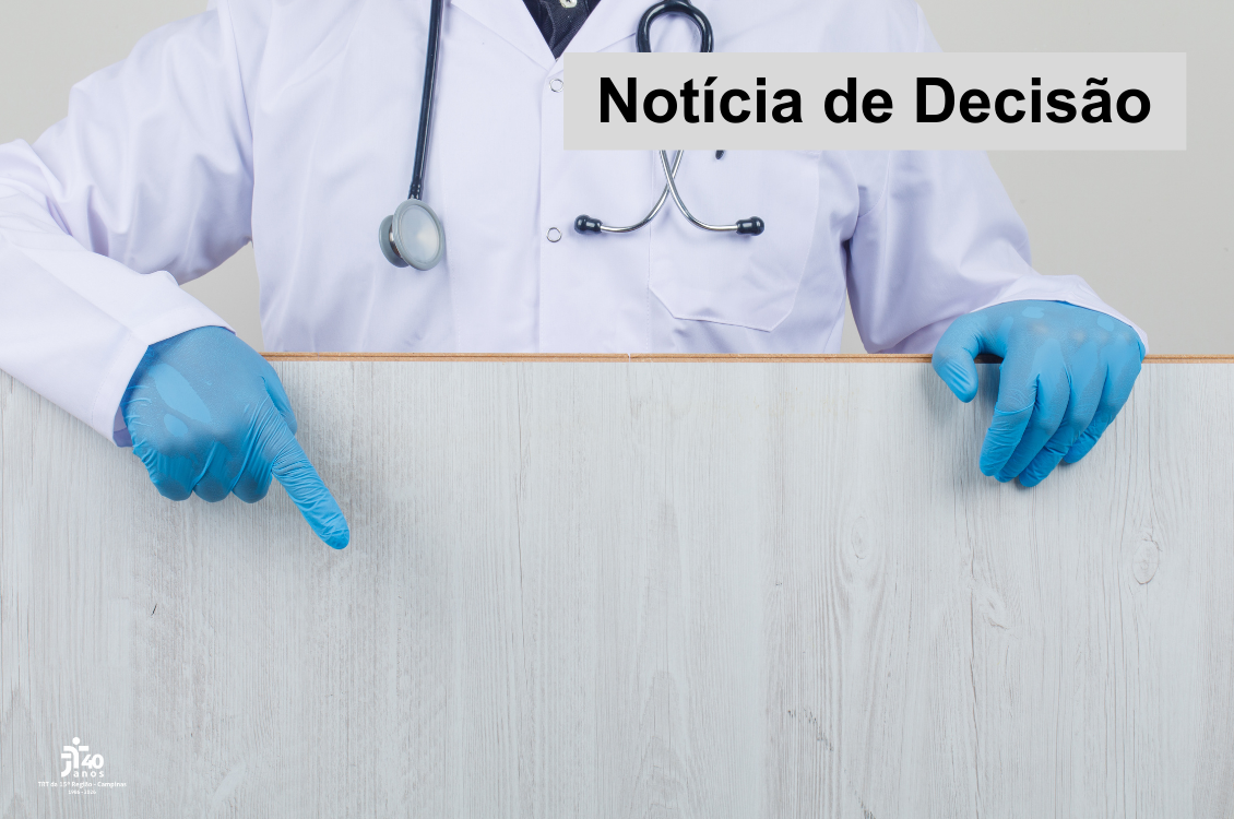 imagem retrata parte do corpo de um homem de jaleco, luvas azuis e estetoscópio atrás de uma placa de madeira texturizada de cinza