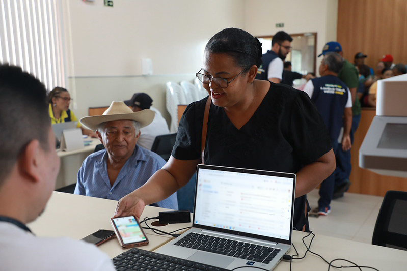 Senhora é atendida em guichê da Justiça do Trabalho por um homem que está em frente a um notebook
