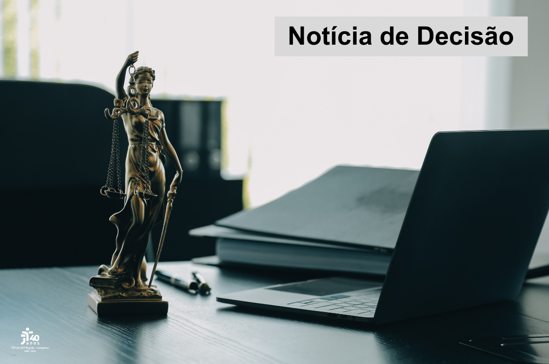 estátua da justiça sobre a mesa de um juiz, que ainda tem papéis e um notebook