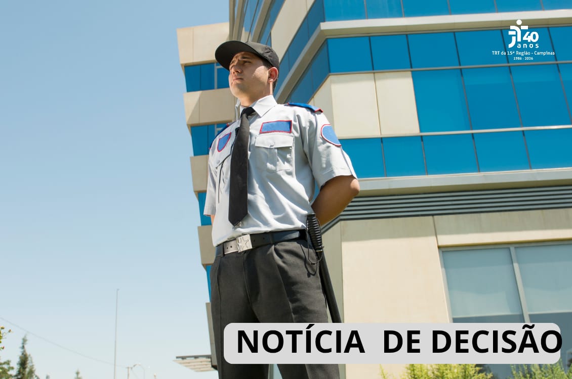 Um homem com uniforme de segurança em frente à uma universidade.