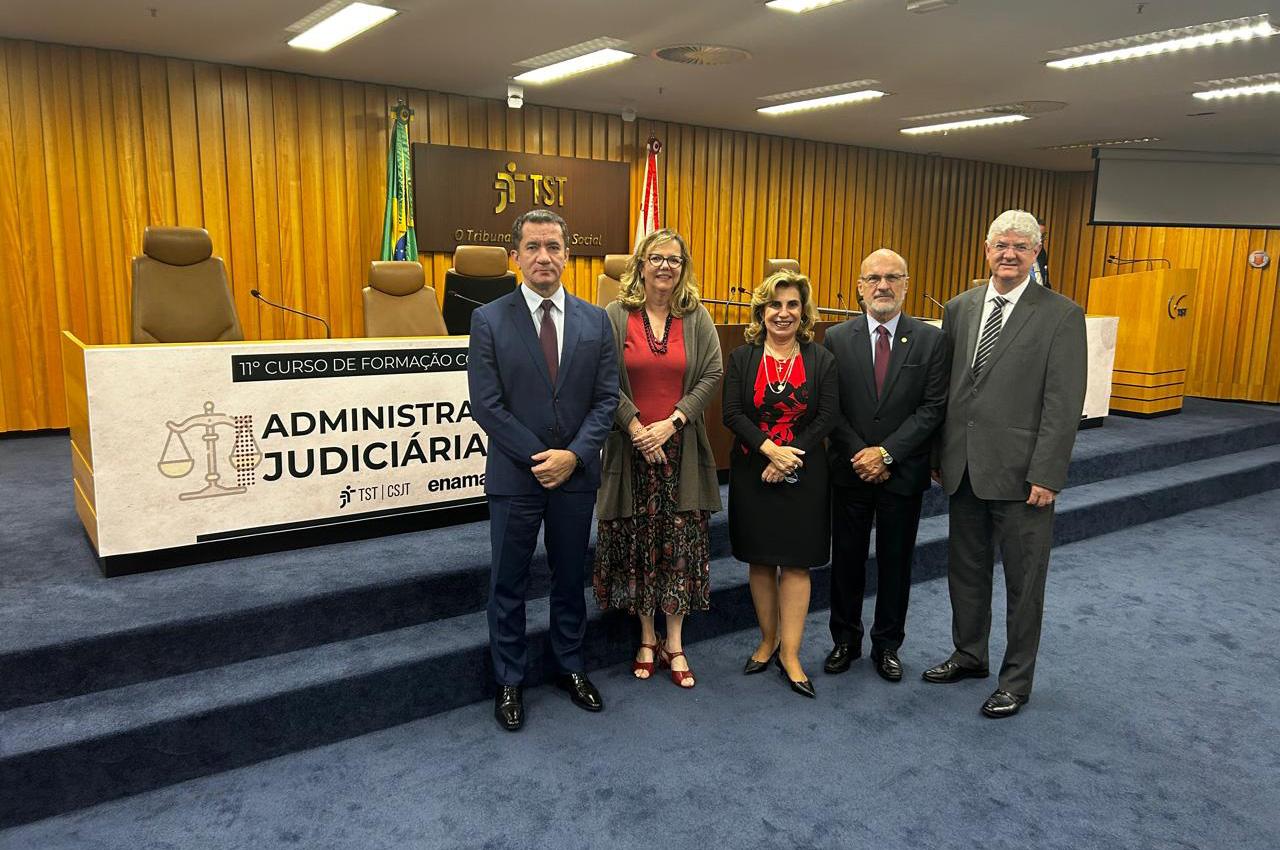 membros do TRT-15 posam para foto no auditório do curso. Ao fundo, faixa alusiva ao evento.