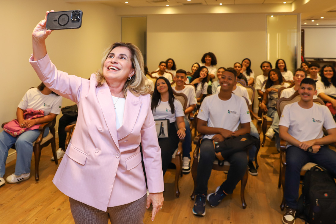 Dra. Ana Paula tira selfie com os aprendizes que estão sentados nas cadeiras do salão nobre