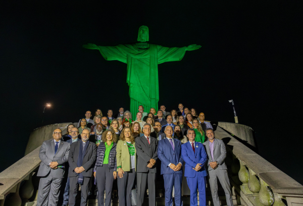 foto noturna de autoridades aos pés do Cristo Redentor iluminado de verde