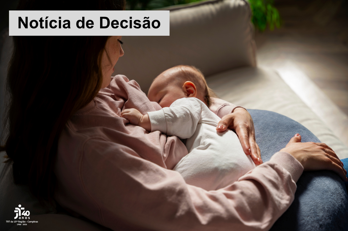 Mulher de blusa rosa está sentada no sofá amamentando um bebê