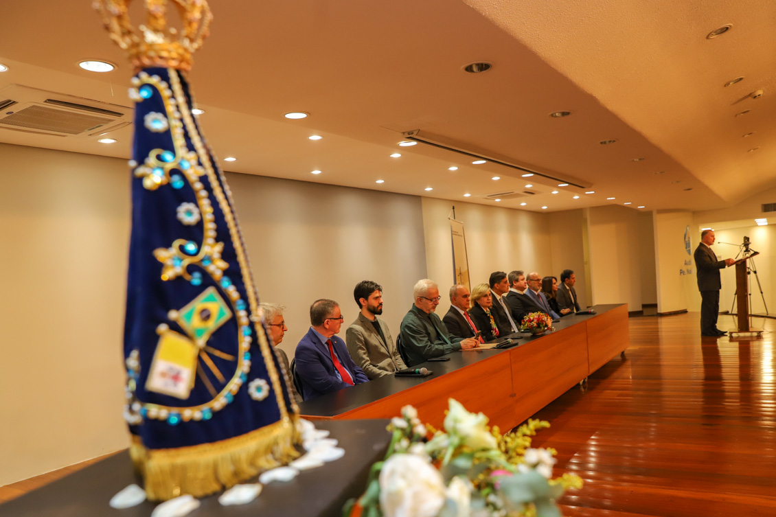 #ParaTodosVerem: mesa de honra com integrantes sentados. à frente, à esquerda, a imagem de Nossa Senhora Aparecida.