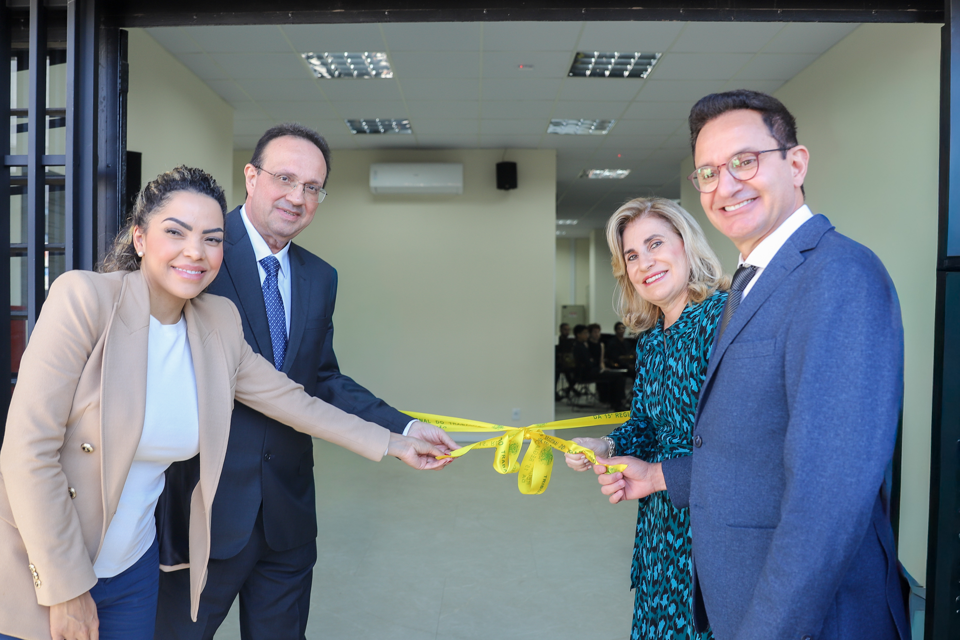 Quatro pessoas, dois homens e duas mulheres desfazem o laço inaugural na porta do novo prédio.
