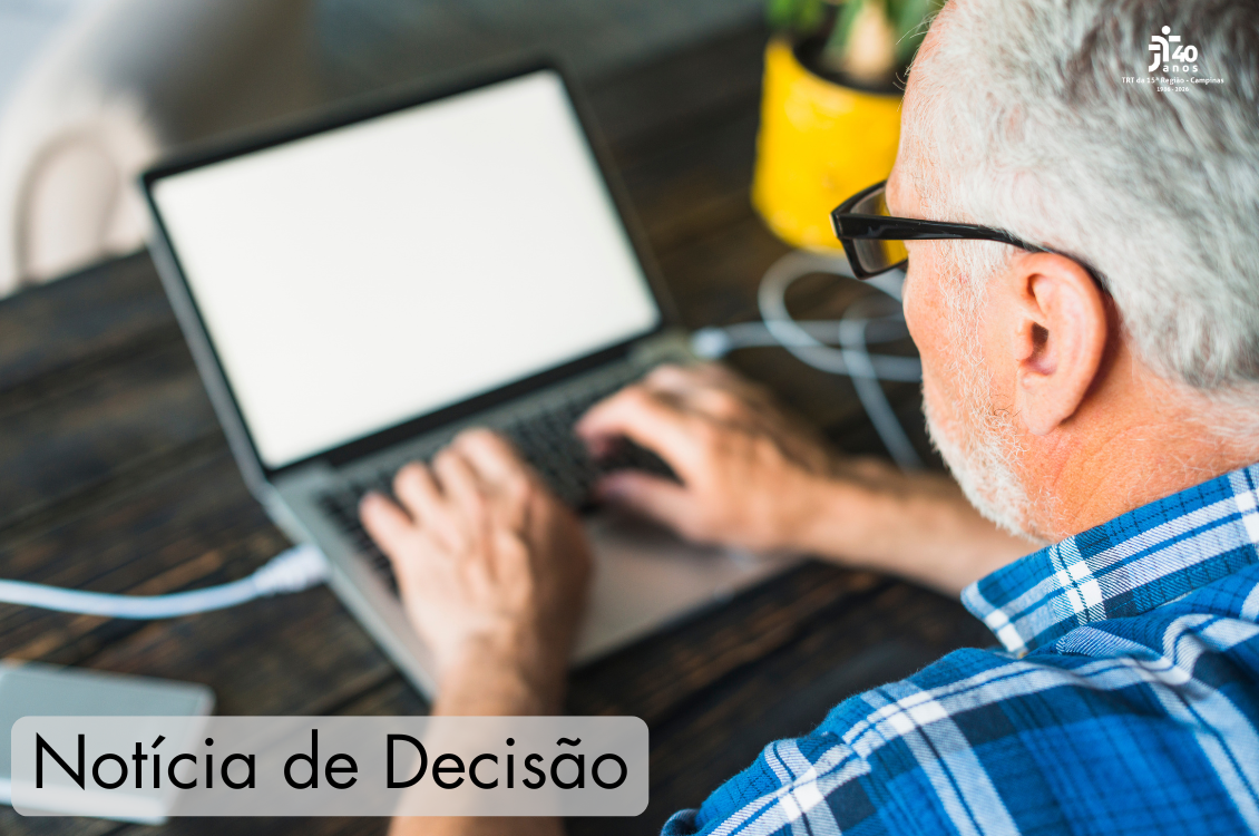 A foto mostra um trabalhador na faixa dos 65 anos de idade trabalhando num computador
