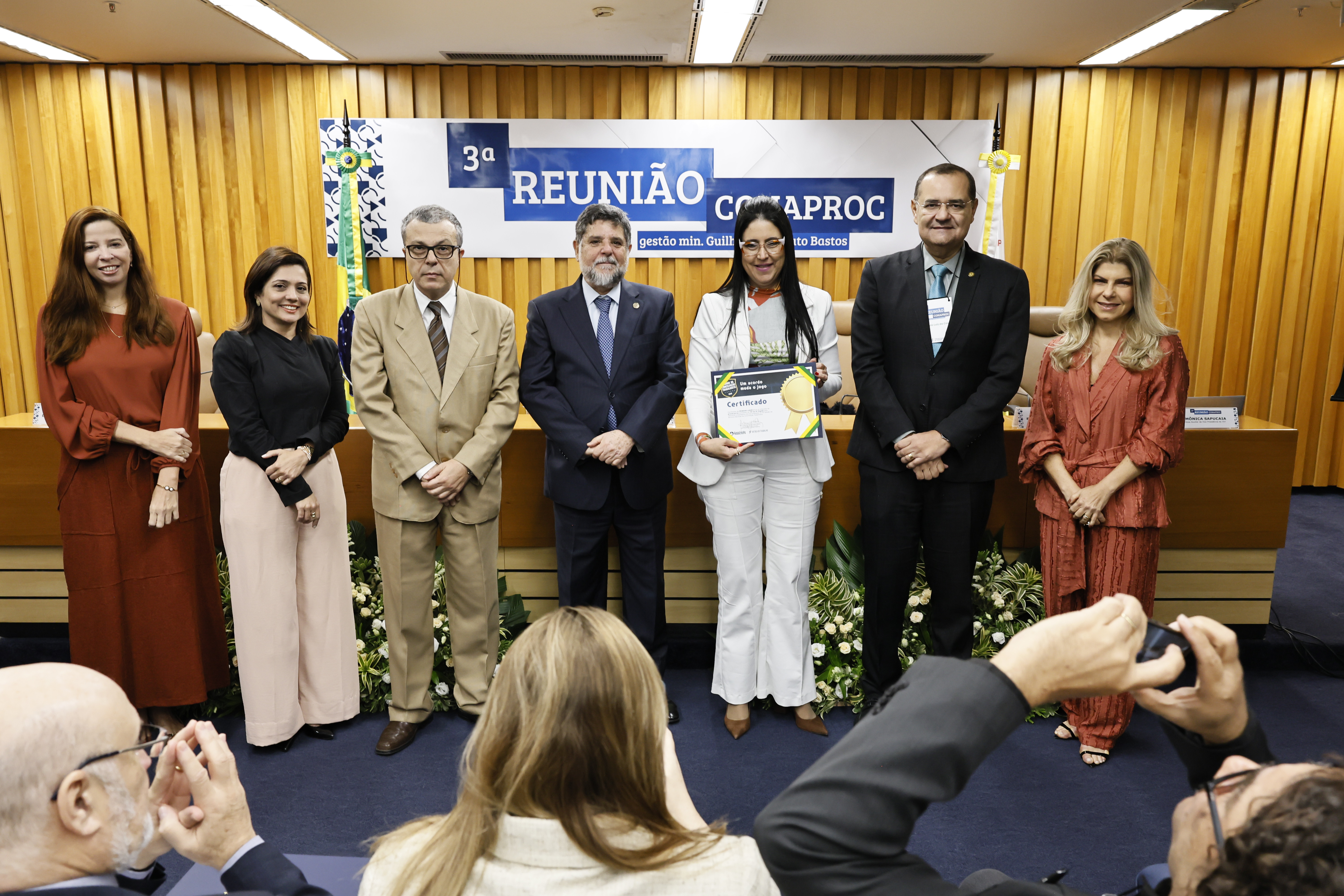 foto posada da Dra. Ana Cláudia com o certificado em mãos, ao lado do ministro Caputo Bastos e outras cinco pessoas