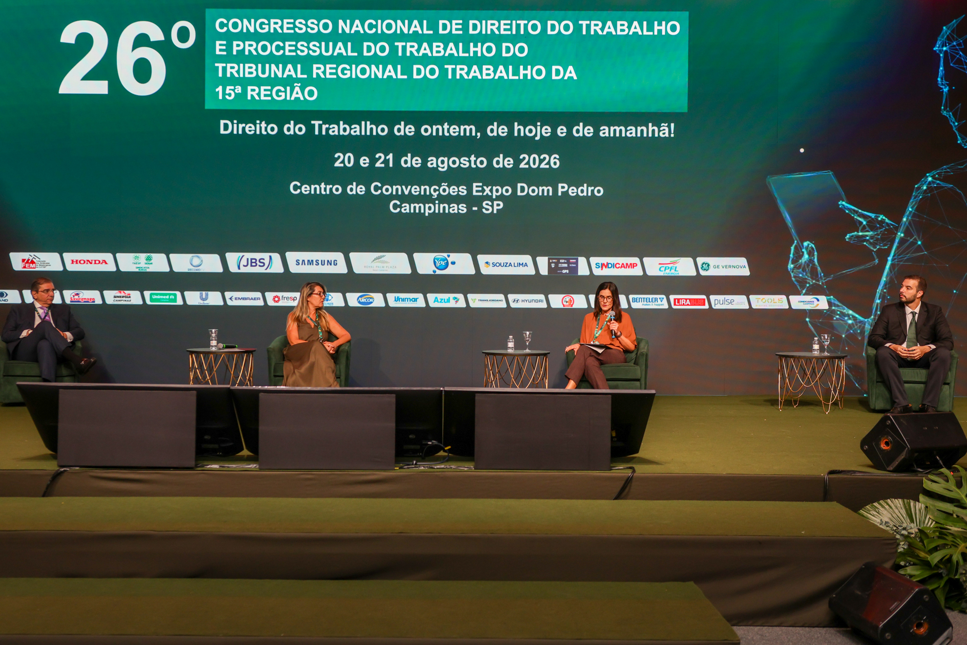 palestrantes em suas poltronas no palco, com telão temático do congresso em tom de verde ao fundo