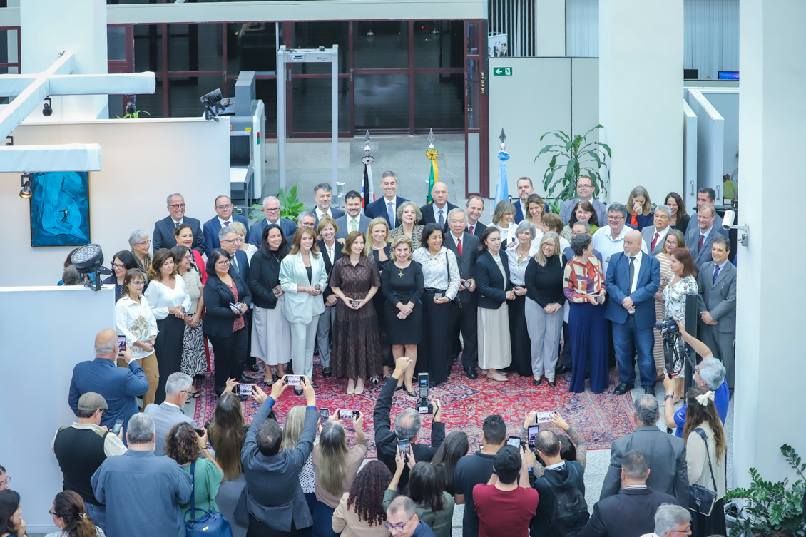 Uma foto do alto com os servidores segurando suas respectivas medalhas. Todos em pé posam para a foto.