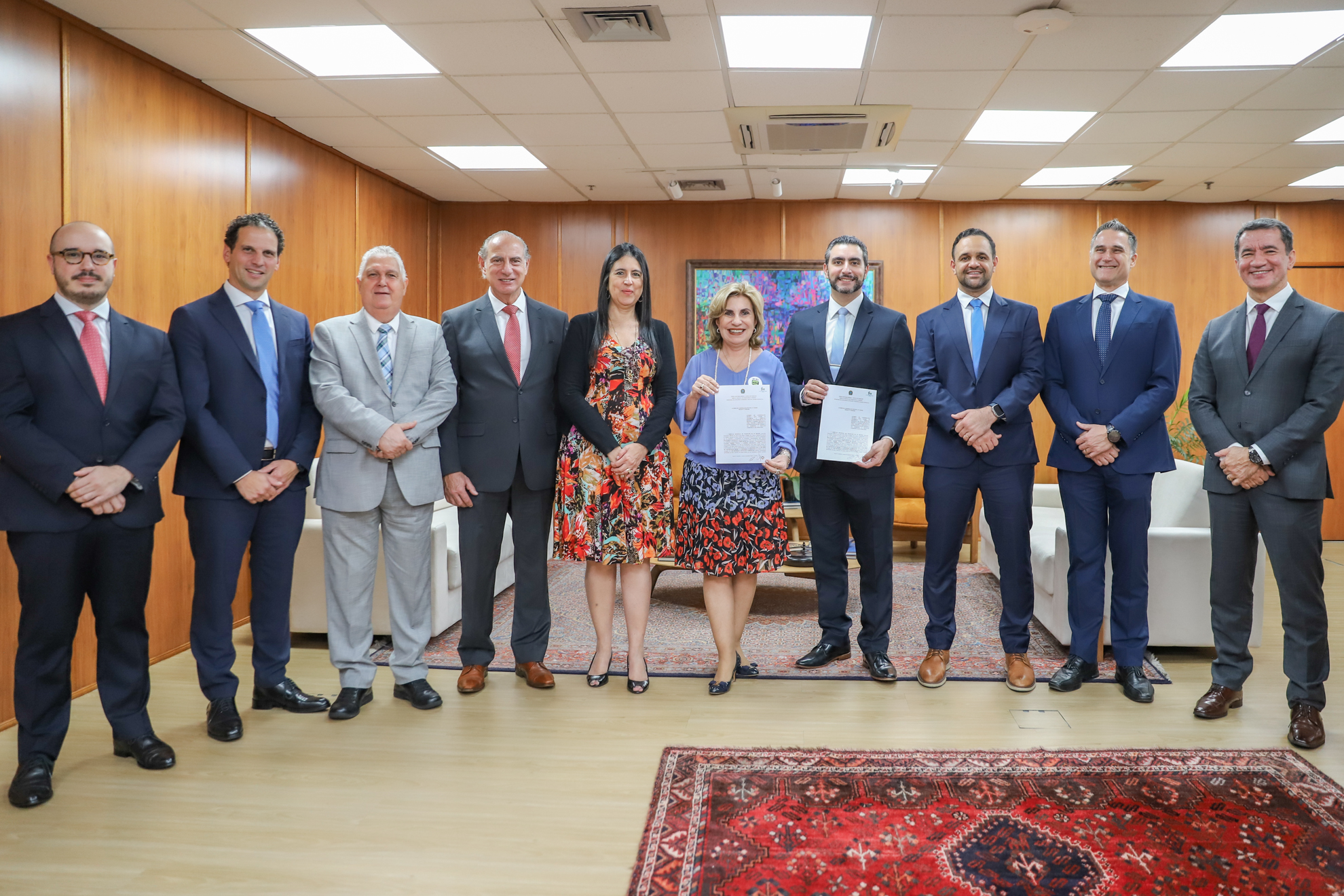 participantes de pé com Dra. Ana Paula e Ricardo de Vasconcelos segurando o termo assinado