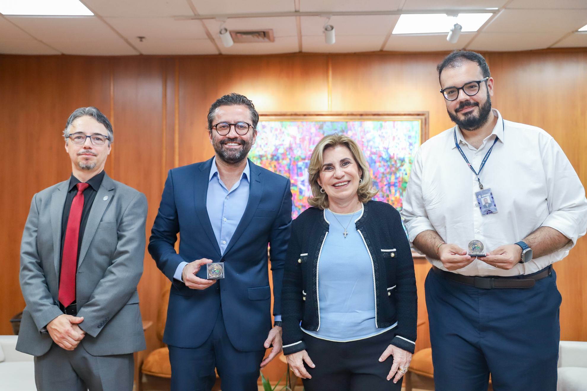 Cleber, Dra. Ana Paula e os visitantes Vinicius e Fernando segurando as moedas, 