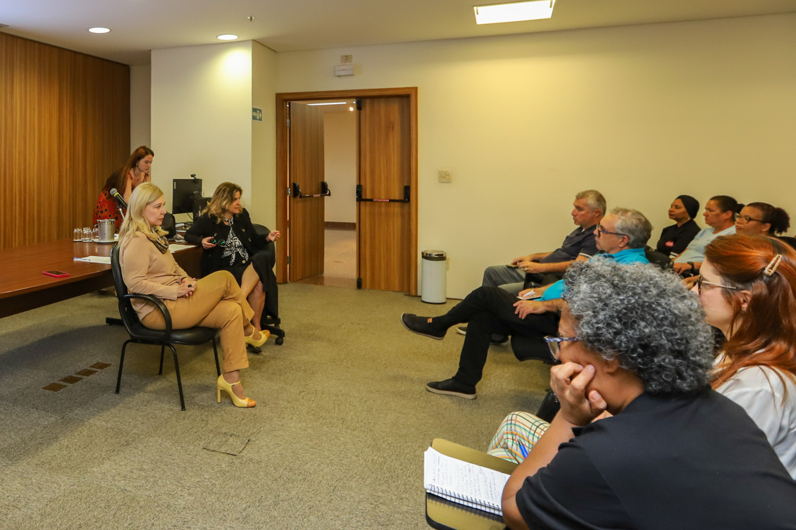 "Desembargadora Antonia, Dra. Dora e Carolina conversam com os participantes que estão sentados em cadeiras do auditório"