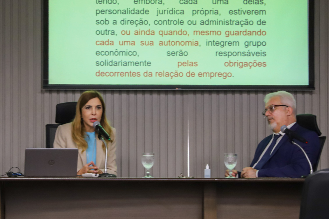 "Palestrante fala ao microfone ao lado do diretor da Ejud."