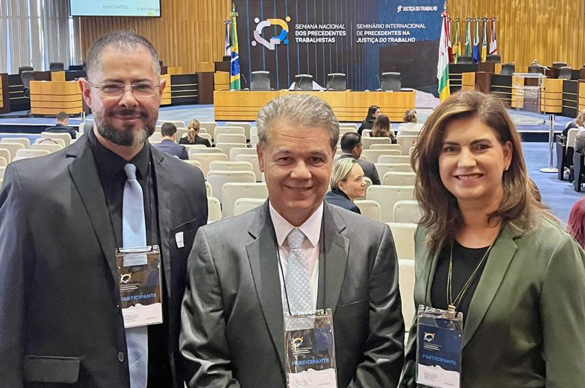 "Dra. Ana Cláudia posa para foto com dois participantes no auditório do TST"