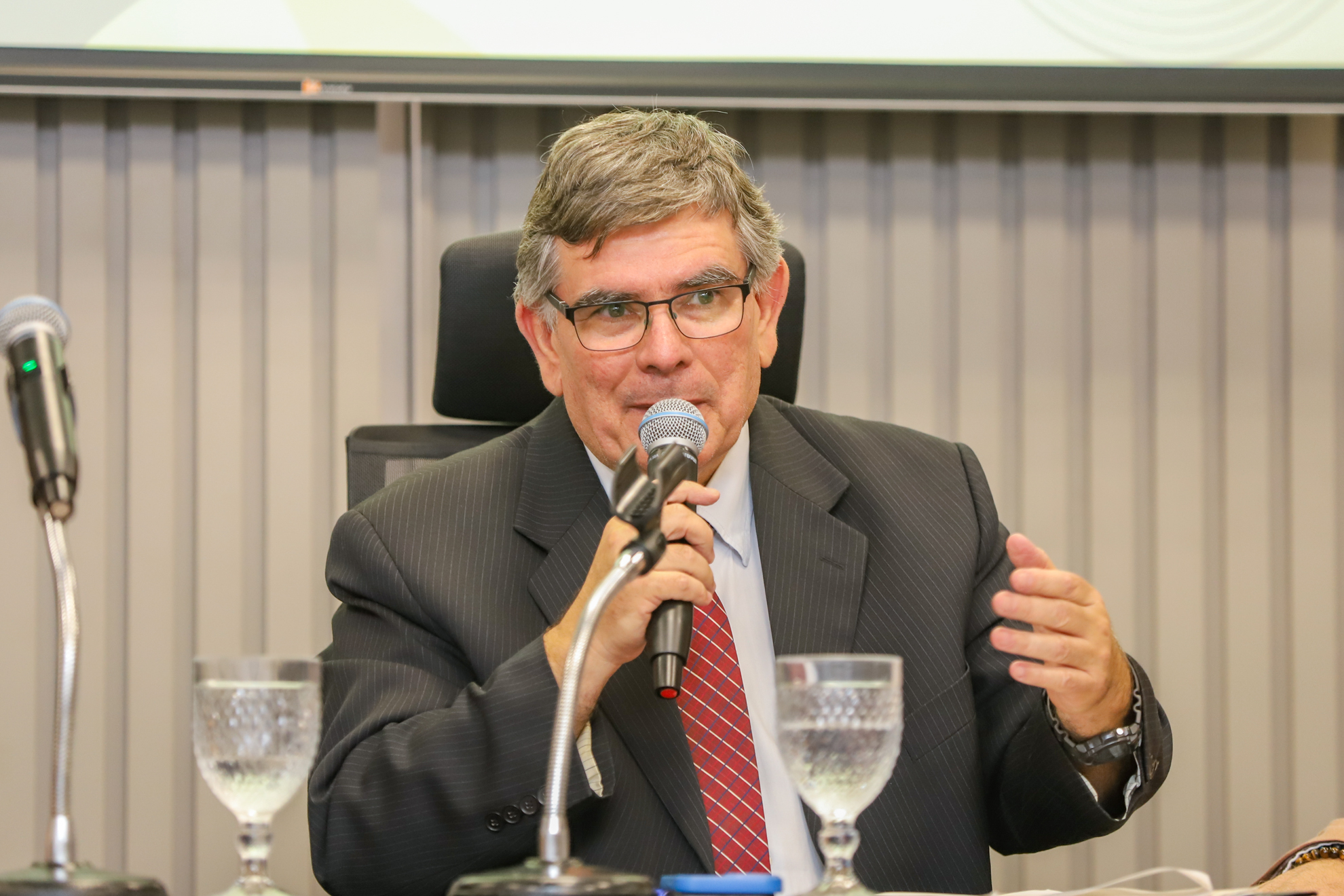 "Dr. João Alberto está na mesa alta falando ao microfone"