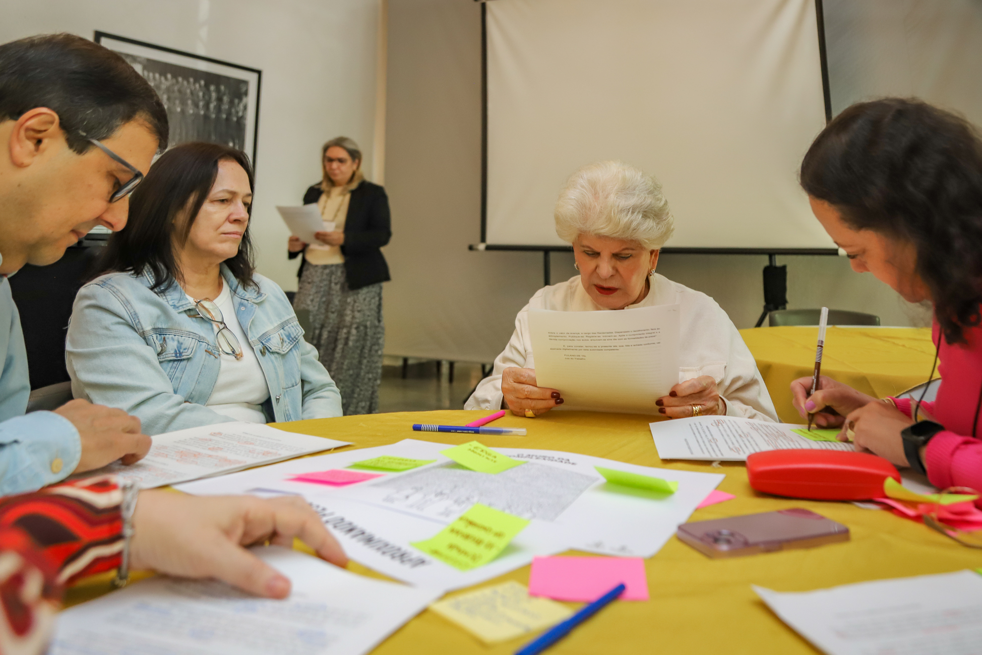 "Magistrados sentados à mesa, que com papéis e post-its coloridos"