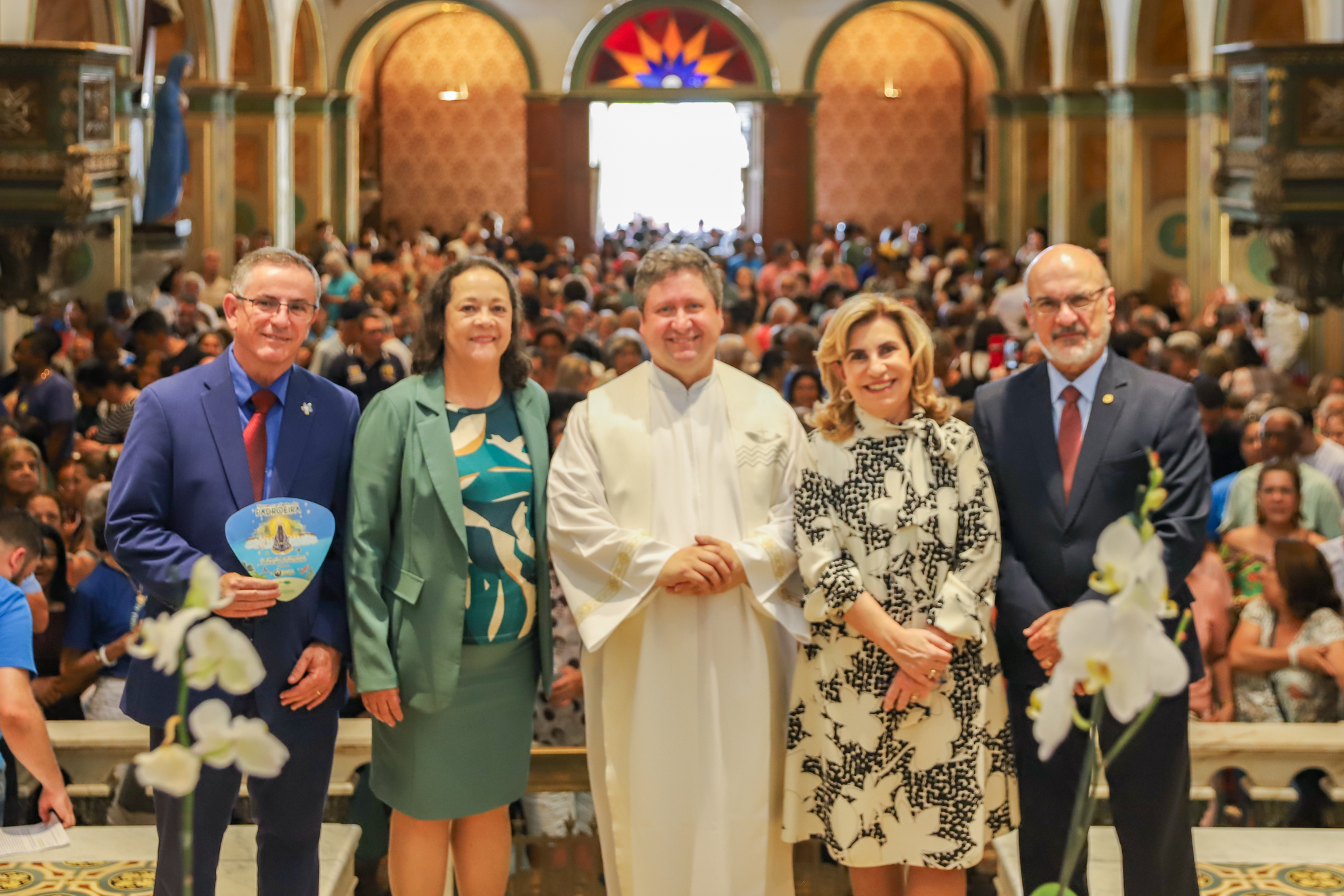 "Comitiva do TRT-15 posa para foto com o padre Catalfo. Ao fundo, a igreja lotada de fiéis"