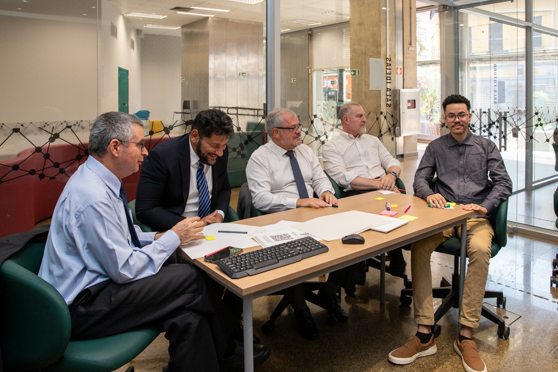 "Quatro homens estão sentados à mesa, participando da oficina"