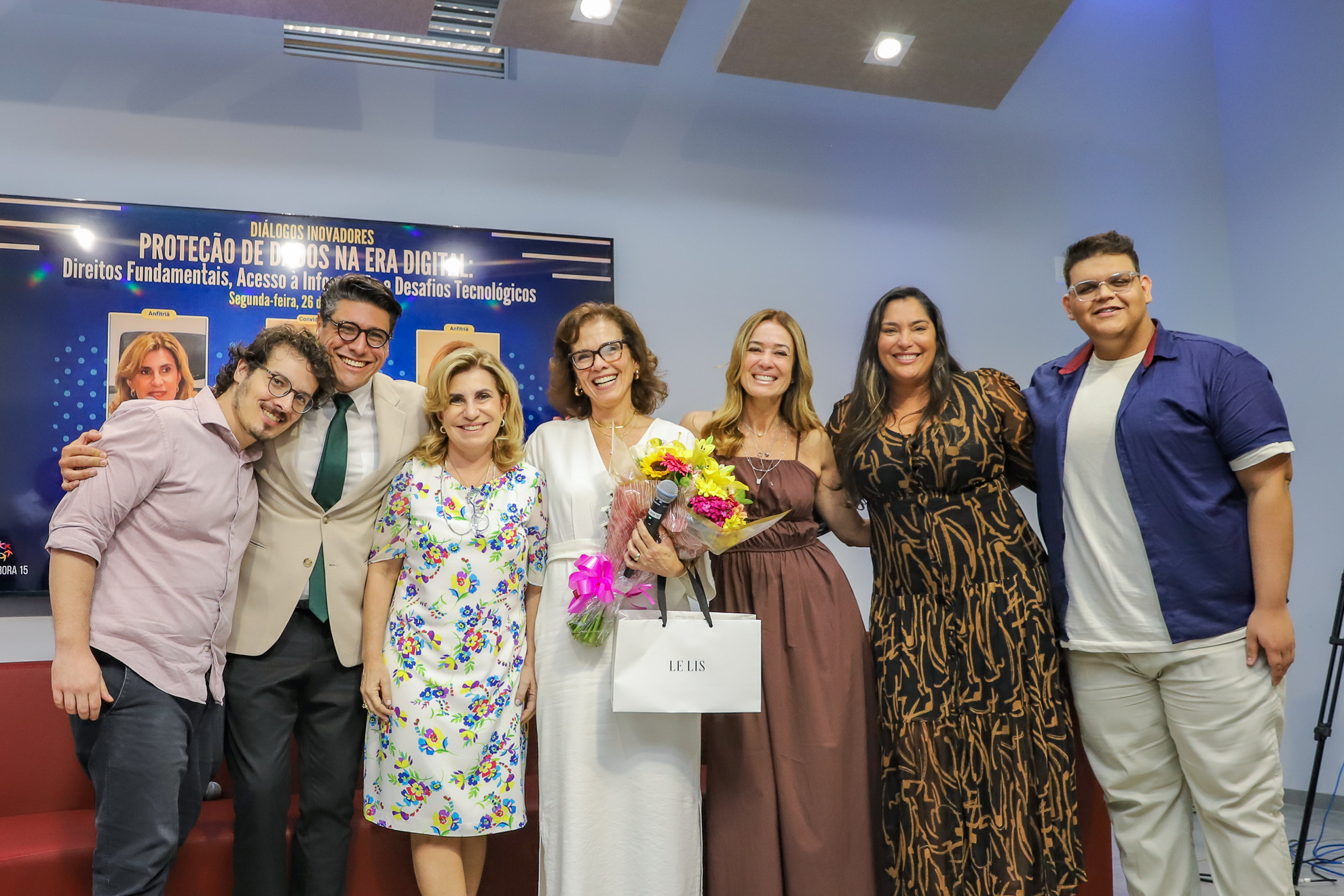 "Equipe do Colabora com o juiz Marcel, Dra. Ana Paula e Dra. Daniela. Lara, ao centro, segura um buquê de flores do campo"
