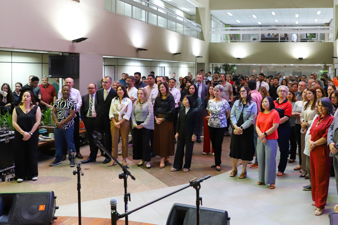 "Dezenas de servidores estão de pé no Espaço de Convívio, atentos às palavras da dra. Ana Paula"