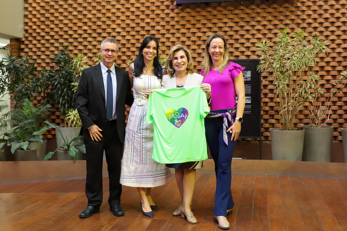 "Dra. Ana Paula segura camiseta da Semana do Servidor, ao lado dos integrantes da Comissão Organizadora, Luiz, Renata e Juliana"