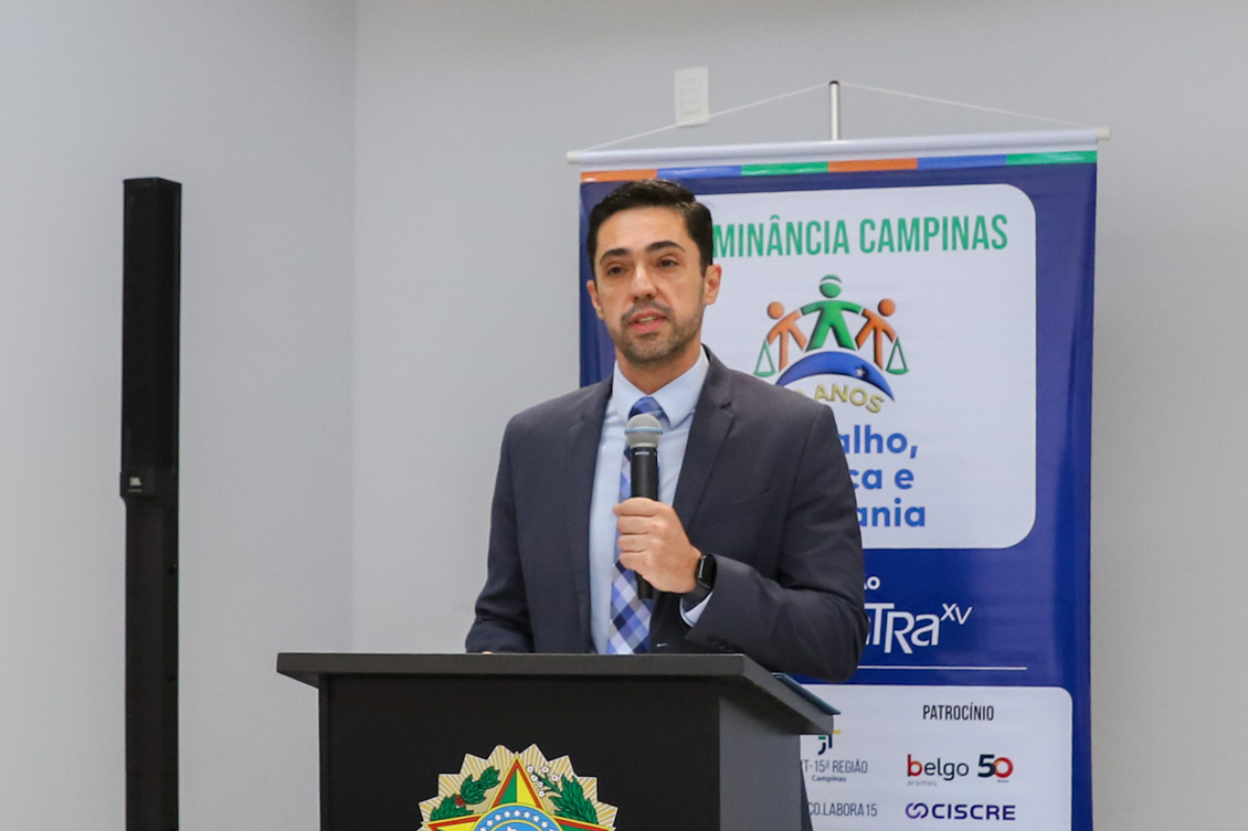 "Juiz Francisco está no púlpito, falando ao microfone. Banner alusivo ao projeto ao fundo, em azul"